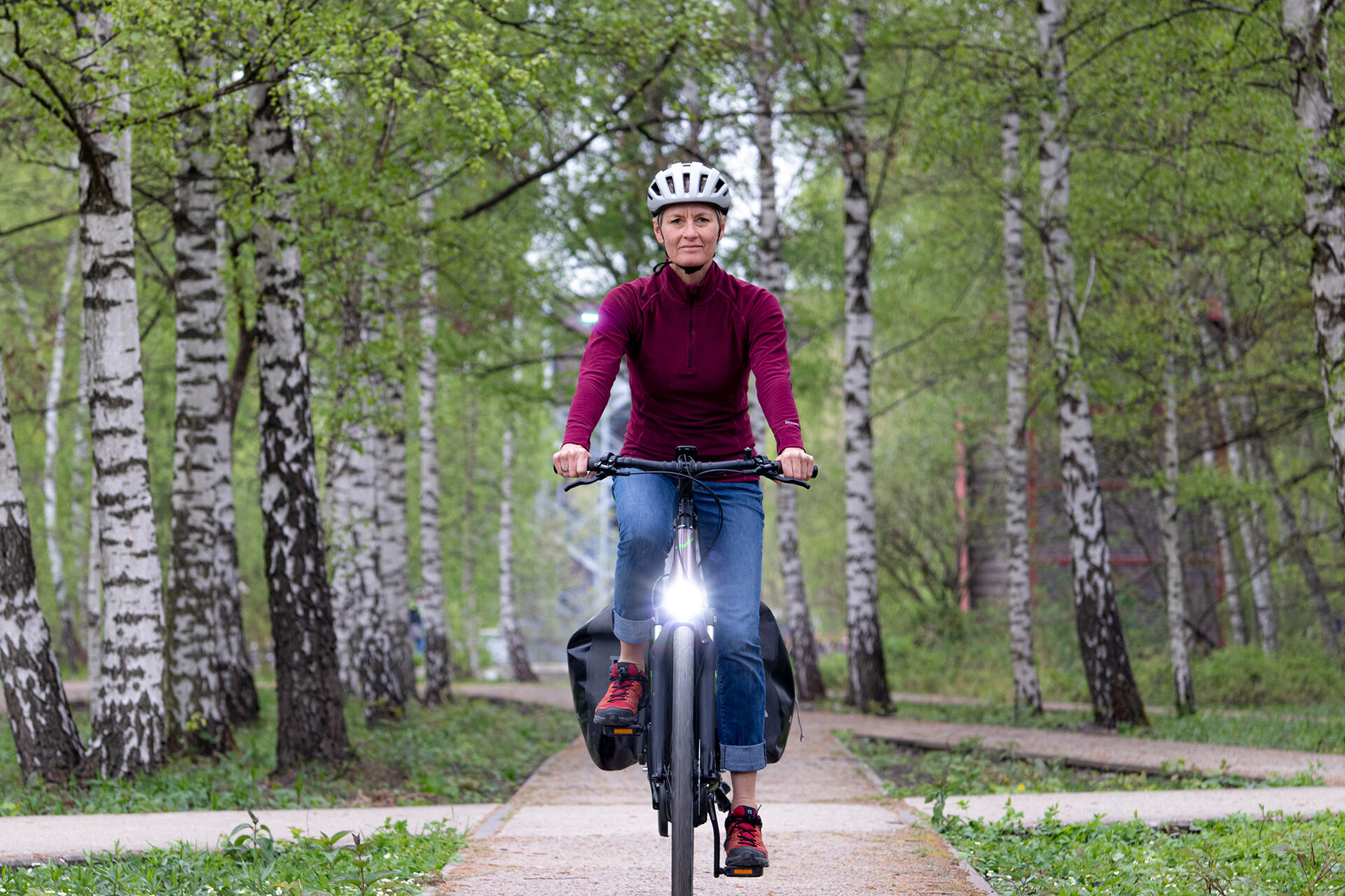 Eine Frau fährt mit einem E-Bike durch einen Birkenwald