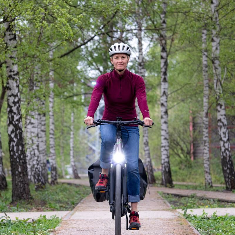 Eine Frau fährt mit einem E-Bike durch einen Birkenwald