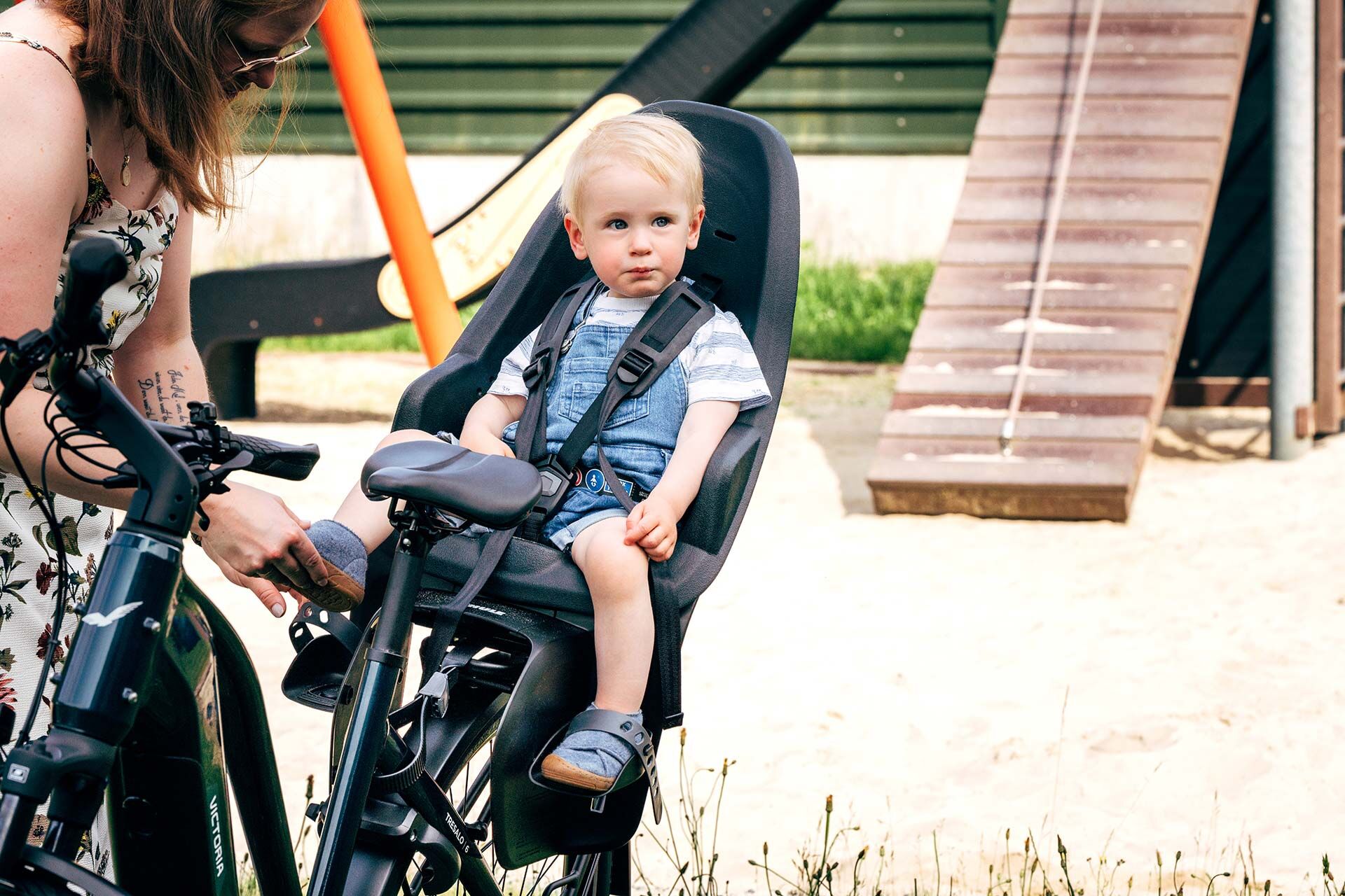 Ein Junge sitzt in einem Kindersitz auf dem Gepäckträger eines E-Bikes