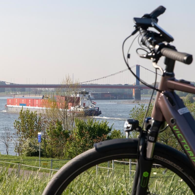  E-Bike steht im Vordergrund, im Hintergrund ist die Haus-Knipp-Eisenbahnbrücke zu erkennen