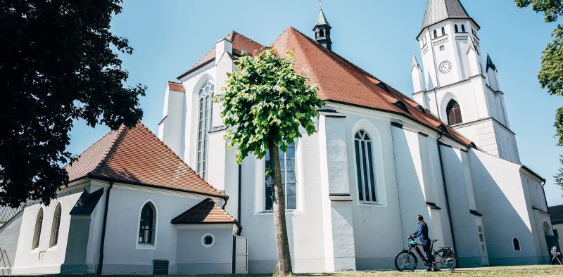 Frau steht mit einem E-Bike vor der Kirche in Wittichenau