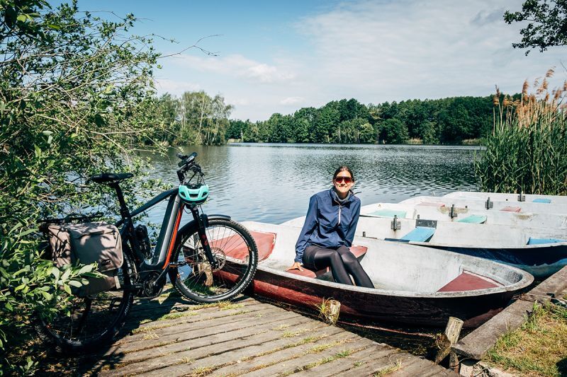 Radfahrerin sitzt in einem Ruderboot auf einem Teich